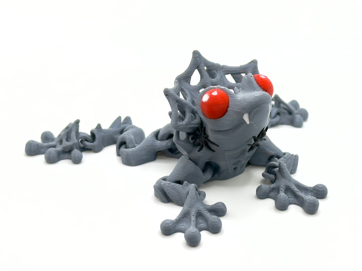 Count Frogula grey with red eyes front. Count Frogula is a frog with the teeth and "collar" of a vampire.