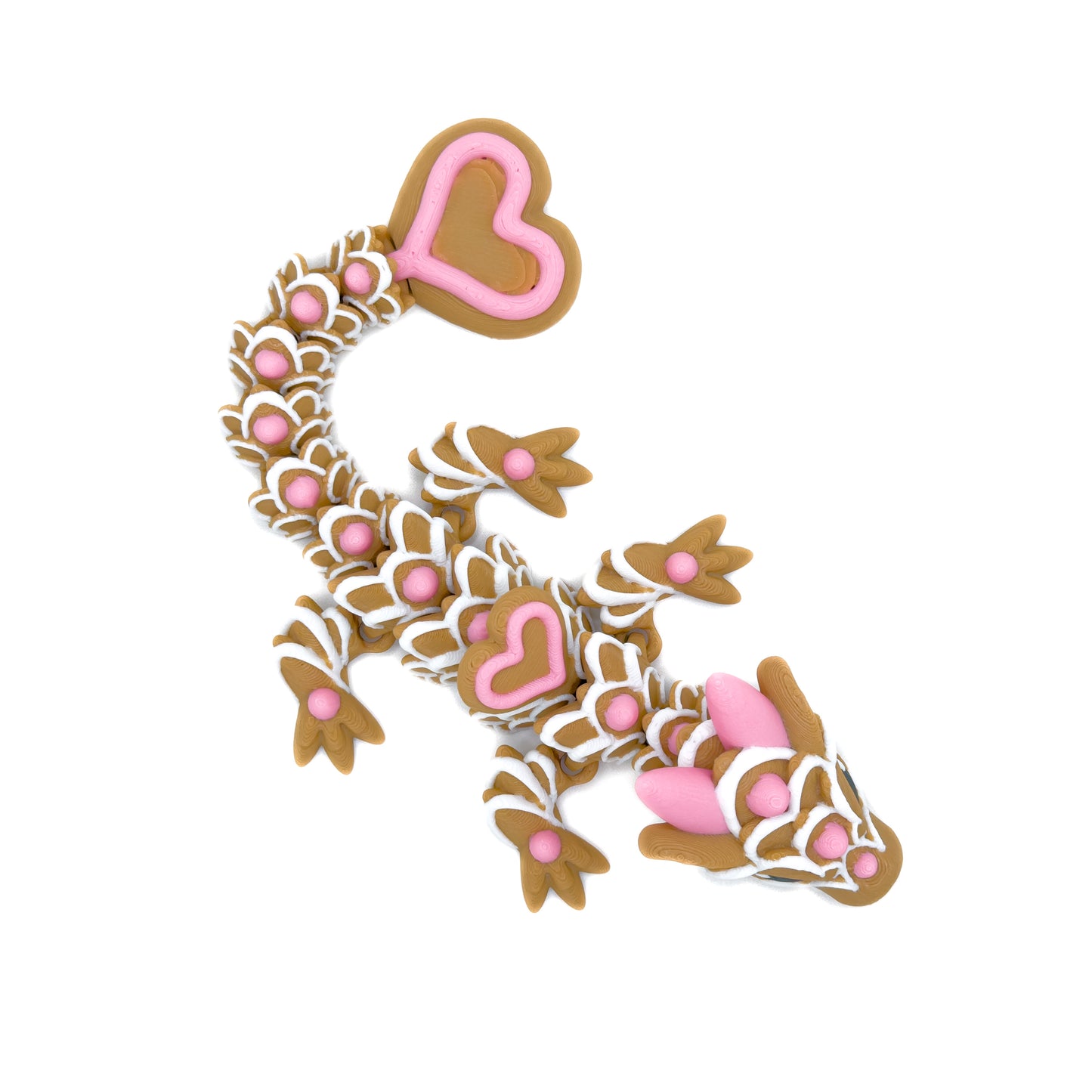 Top-down view of a brown dragon figure featuring white icing-like scales and pink heart accents, with a large heart-shaped tail.