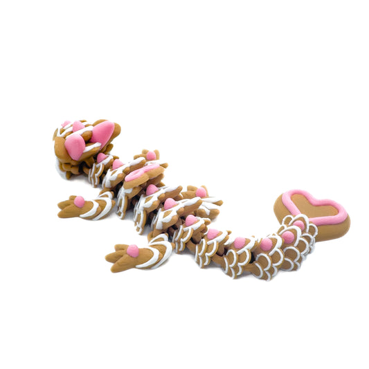 Side view of a brown dragon figure with pink and white heart-shaped details along its body, displayed on a white surface.