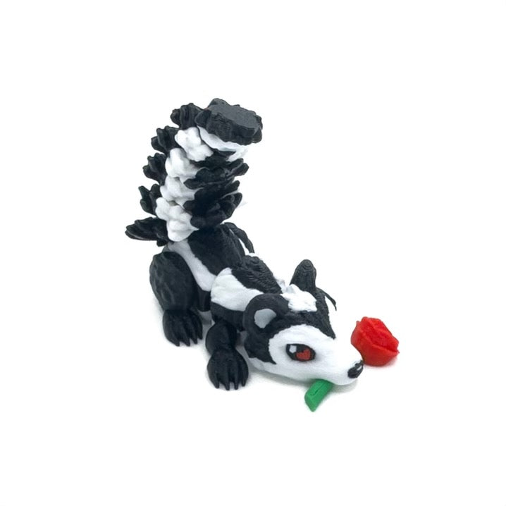 A black-and-white skunk 3D-printed figure with hearts in its eyes holding a red rose in its mouth, positioned on a white background