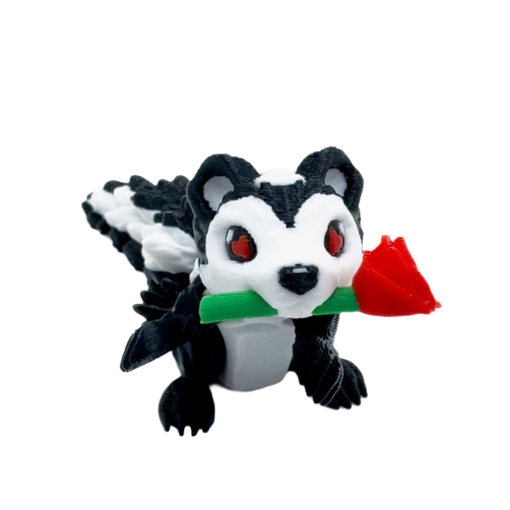 Front view of a black-and-white skunk figure with red eyes and a red rose in its mouth, sitting upright on a white surface.